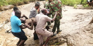 Police officer and local residents rescue a man who was trapped following the landslide that hit West Pokot County on April 18, 2020.