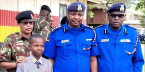 Police officers pose for a photo with Simon Muthama, the needy student they are sponsoring.