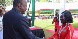 President Uhuru Kenyatta (left) awards the Order of the Grand Warrior of Kenya (OGW) to marathoner Mary Jepkosgei Keitany at the Jamhuri Day celebrations garden party at State House, Nairobi on December 12, 2019.