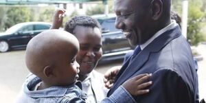 President William Ruto holding Ian Kipkoech alongside his mother in 2019.