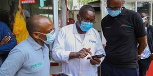 Safaricom PLC CEO Peter Ndegwa (Left) and Consumer Business Unit Director Charles Kare get feedback from a customer.