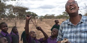 Teddy Kinyanjui, co-founder of Seedballs Kenya (extreme right) smiles as kids sling seedballs in the countryside.