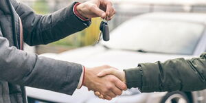 Two people shaking hands over car deal. Getty.