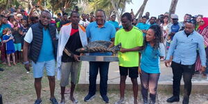 Former President Uhuru Kenyatta (centre) poses for a photo during the Diani Regatta Ngalawa festival on February 19, 2023.