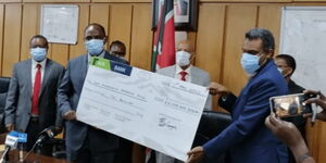 DPP Noordin Haji (right) presents a Ksh.2 billion dummy cheque to Treasury CS Ukur Yatani on April 7, 2020