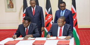 Governor Mike Mbuvi Sonko and Devolution CS Eugene Wamalwa signing an agreement in State House on Tuesday, February 25.