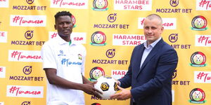 Mozzart official (right) hands over a ball to Harambee Stars player Michael Olunga 