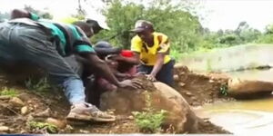 Murang'a residents move stones used in constructing a dam in an attempt to drain it. 