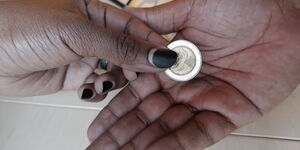 A photo of someone paying using Ksh20 coin