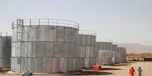 Workers walk past storage tanks at Tullow Oil's Ngamia 8 drilling site in Lokichar, Turkana County.