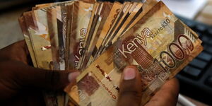 A person holding 1,000 Kenyan shillings notes