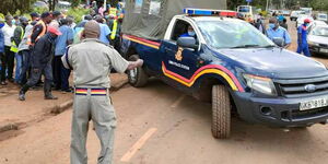 A police vehicle surrounded by residents during a crime scene