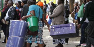 A parent assisting a student carry a box during a Form One admission exercise.