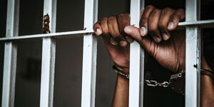 A man's hand cuffed inside a police cell