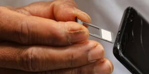 A photo of a man inserting a sim card in a phone
