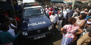 A photo of a police car and locals at a past crime scene