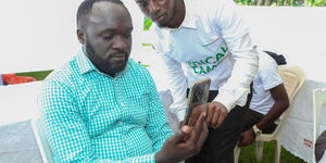 Bungoma Senator David Wakoli Wafula(L) assisted on how to operate AI heart Monitor App by health worker Peter Ndegwa(R). The APP help to monitor blood pressure, heart rate and pulse rate. This was at an M-PESA Foundation medical camp in Bungoma County.