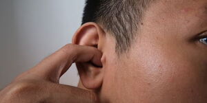 An image depicted a man inserting a finger inside his ear.