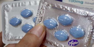 A photo of a person holding a sachet of Sildenafil tablets.