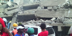Residents pass by a building that collapsed and trapped construction workers behind Thika Road Mall in Roysambu on April 2, 2015.