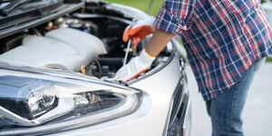 A driver checking a parked car before starting the engine