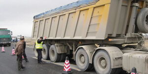 A truck drives on a mobile dynamic axle weighing system laid flat on the road.