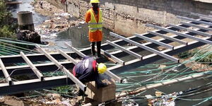A photo of workers constructing a new permanent foot bridge linking Kenya Wine, Fuata Nyayo slums and Enterprise Road in Nairobi's Industrial Area on February 25, 2020.