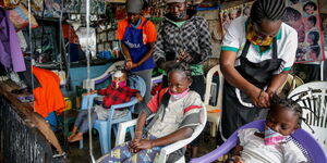 Gettrueth Ambio (C), Jane Mbone (R), and Hamida Bashir (L), have their hair styled in the shape of the coronavirus, at the Mama Brayo Beauty Salon in Kibera slum,Nairobi on May 3, 2020