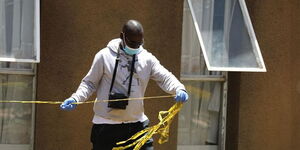 A detective attached to the Directorate of Criminal Investigations (DCI) cordones off an area as a crime scene in October 2021.