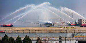 An image of a plane being saluted by water sprays.