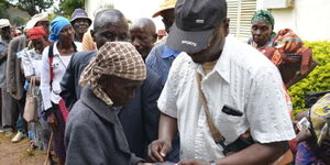 INUA JAMII: KCB employee at Mwingi branch pays elderly citizens their monthly stipend.