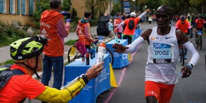 Eliud Kipchoge (right) receives a bottle of water during the 2022 Berlin Marathon staged on Sunday, September 25 in Germany.