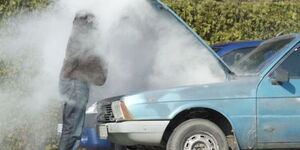 An image showcasing an individual attending to a vehicle emitting smoke