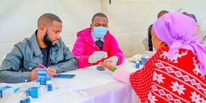 Felix Muchemi (L) and Dalmas Kiplimo (R) attending to a patient during the M-PESA Foundation Medical Camp at Kabete National Polytechnic. 