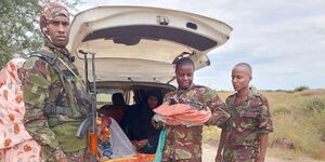 KDF carrying a baby after delivery at the Gherille Forward Operating Base.