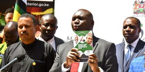 Immigration and Citizen Services PS Julius Bitok displays a copy of a booklet on Frequently Asked Questions (FAQs) on Digital ID to the media at the Nairobi Serena Hotel. Looking on is Amnesty International Kenya Executive Director Irungu Houghton.