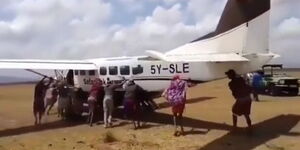 Individuals pushing a stalled plane in Kenya.