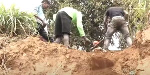 A kin in Gituthia village exhuming a body from grave 