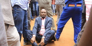 Police officers shielding Gatundu South MP Moses Kuria (seated) from bouncers who wanted to eject him from BBI rally in Kitui on February 1, 2020.