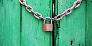 A photo of a door locked with a chain link and a padlock. 