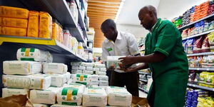 Supermarket attendants restocking maize flour on their shelves.  