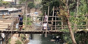 A photo of People crossing on a makeshift foot bridge which is on the verge of collapse in Nairobi's Mukuru slums on February 25, 2020.
