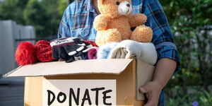 An image of a man holding a box with a teddy bear and giftings.