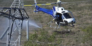 A helicopter flying over powerline during a live line washing 