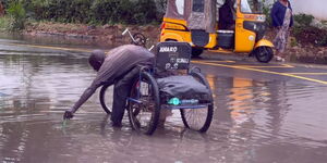 A man in a wheelchair unclogging blocked drainage at Mombasa Law Courts roundabout on Sunday, May 7, 2023.