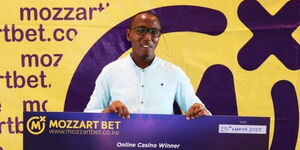 Image of Peter Kirunge receiving his cash prize from Mozzart Bet.
