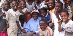 Charles Mully poses for a photo with children from The Mully Children’s Family (MCF) 