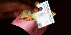 A photo of a Kenyan holding multiple national identity cards