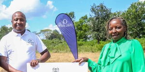 Deputy Head of Sales for Tatu City and Oaklands Samuel Njoroge (left) hands over a symbolic title deed to Rosemary Wairimu, a new Oaklands homeowner.