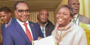 Education Cabinet Secretary Julius Migos Ogamba (Left) posing for a photo with an invigilator